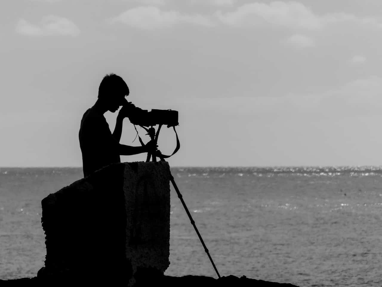 man using a scope to look over the water