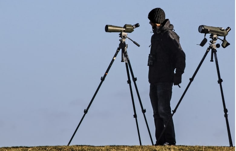 A man with spotting scopes attached to a tripod