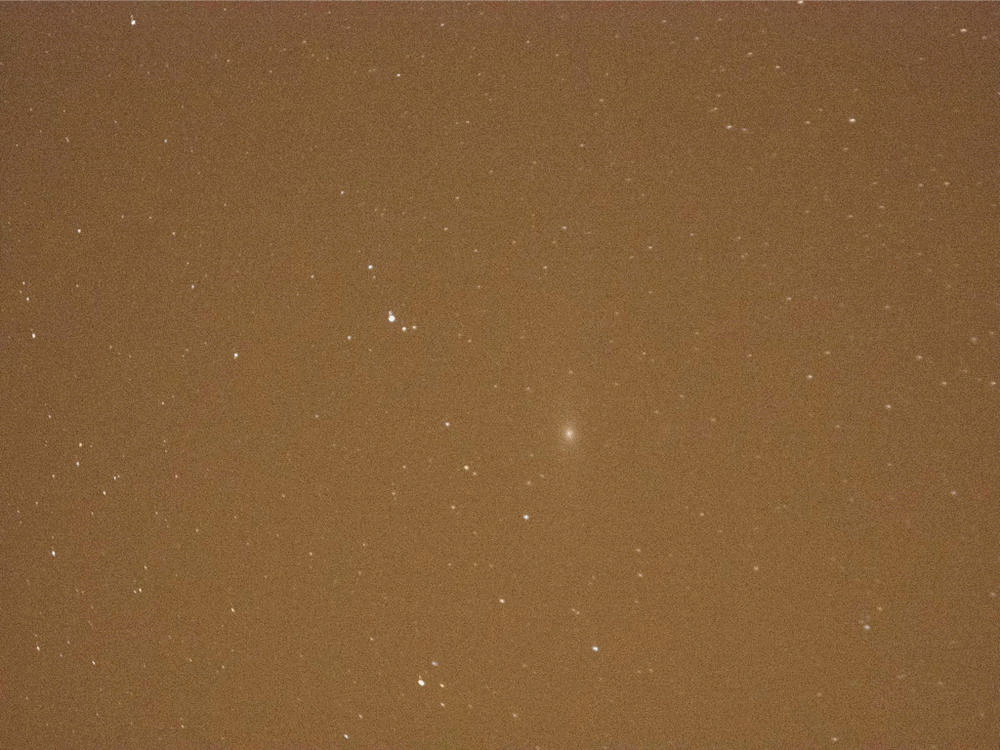Andromeda’s core is barely visible in the orange sky glow.