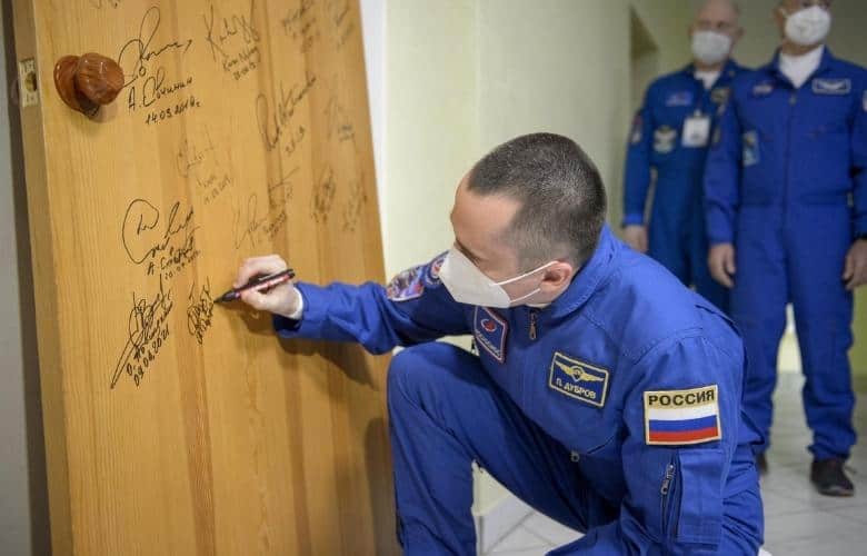 Expedition 65 Russian cosmonaut Pyotr Dubrov performs the traditional door signing at the Cosmonaut Hotel