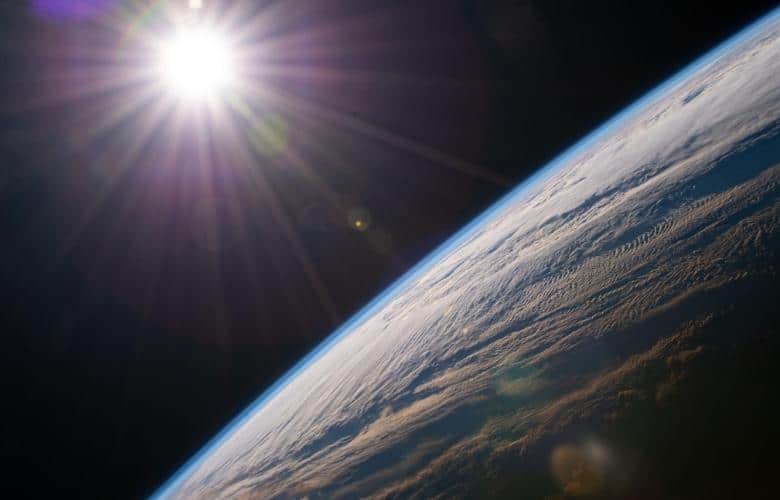 The sun shines above the Earth's horizon as the International Space Station