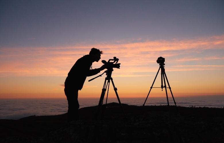A man prepares his camera and tripod for night photography.